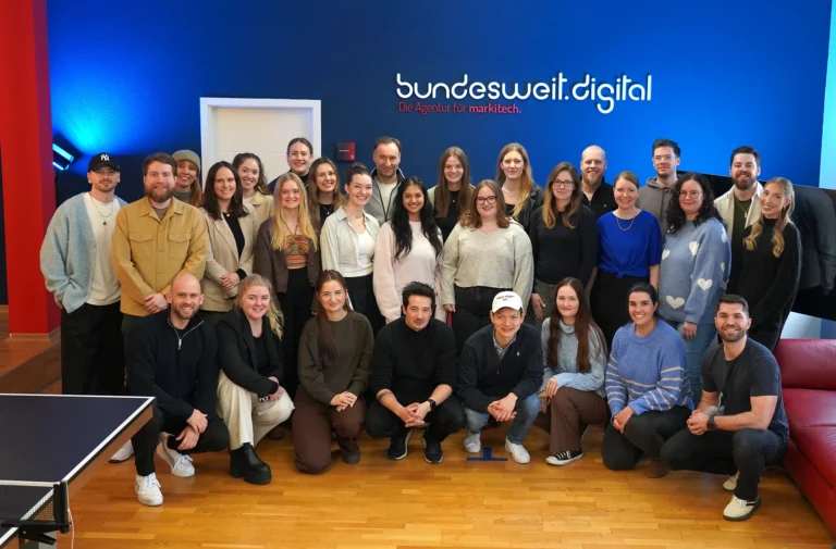 Team der Software-Agentur bundesweit.digital in Hannover vor dem markitech-Logo