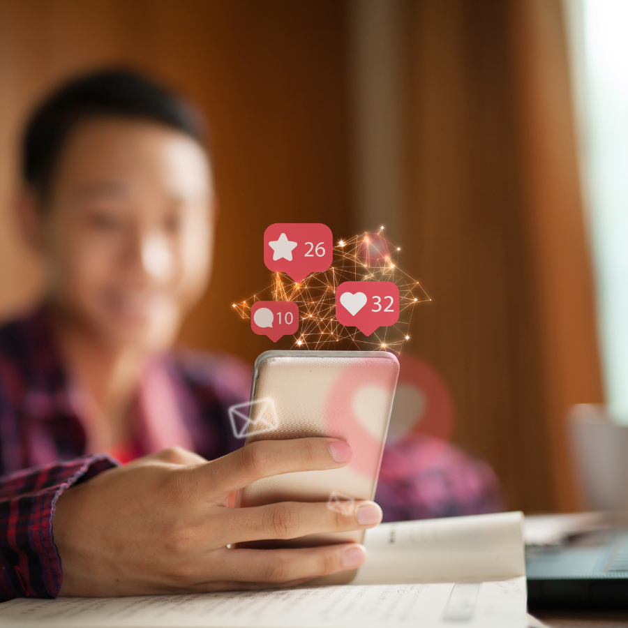 Person hält ein Smartphone, darüber schweben Social-Media-Benachrichtigungen mit Likes, Kommentaren und Favoriten – symbolisiert Reichweite, Engagement und digitale Interaktion im Social-Media-Marketing.